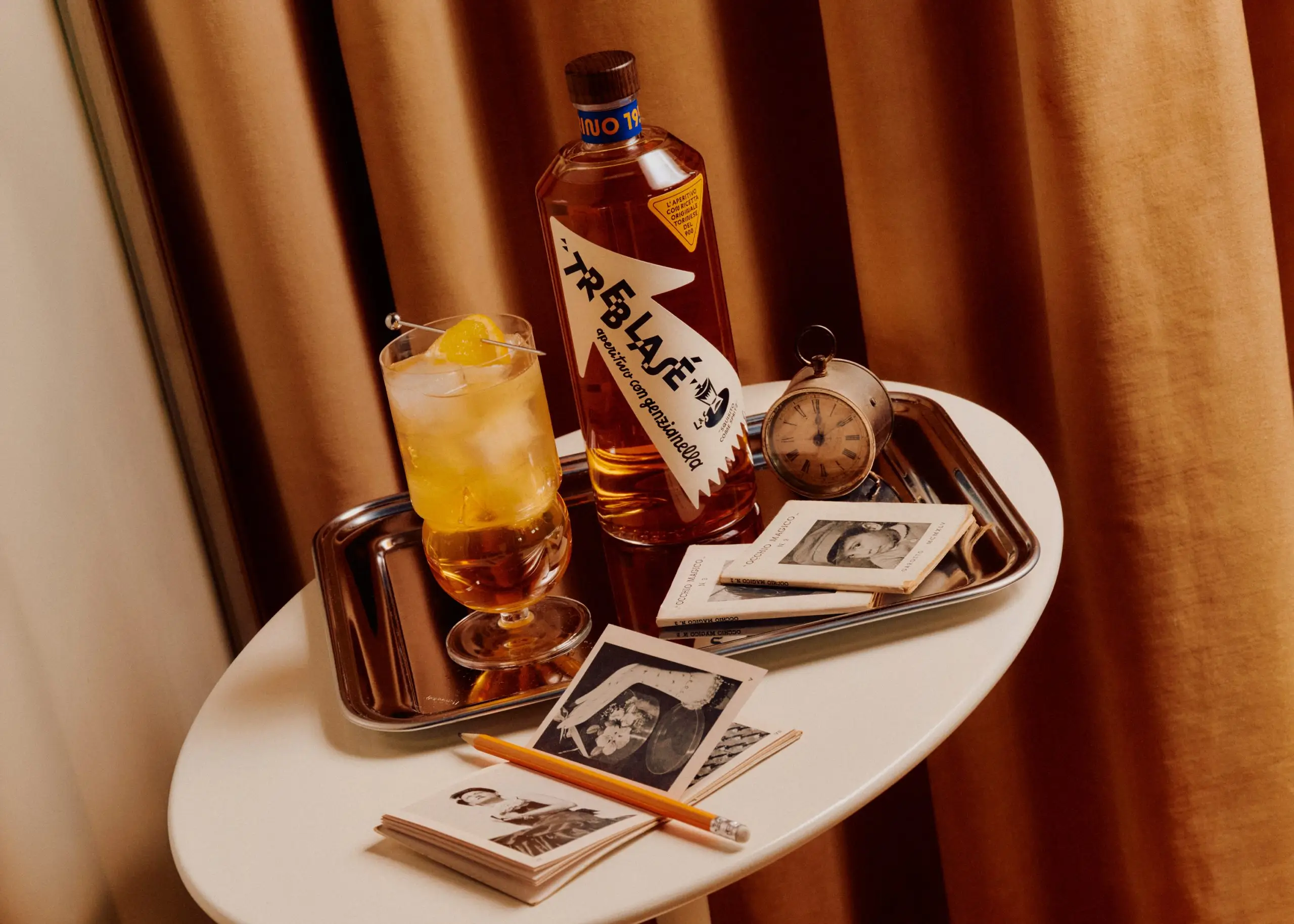 Treblasé aperitivo bottle and glass on a tray, with staggered angular lettering on its arrow-shaped label.